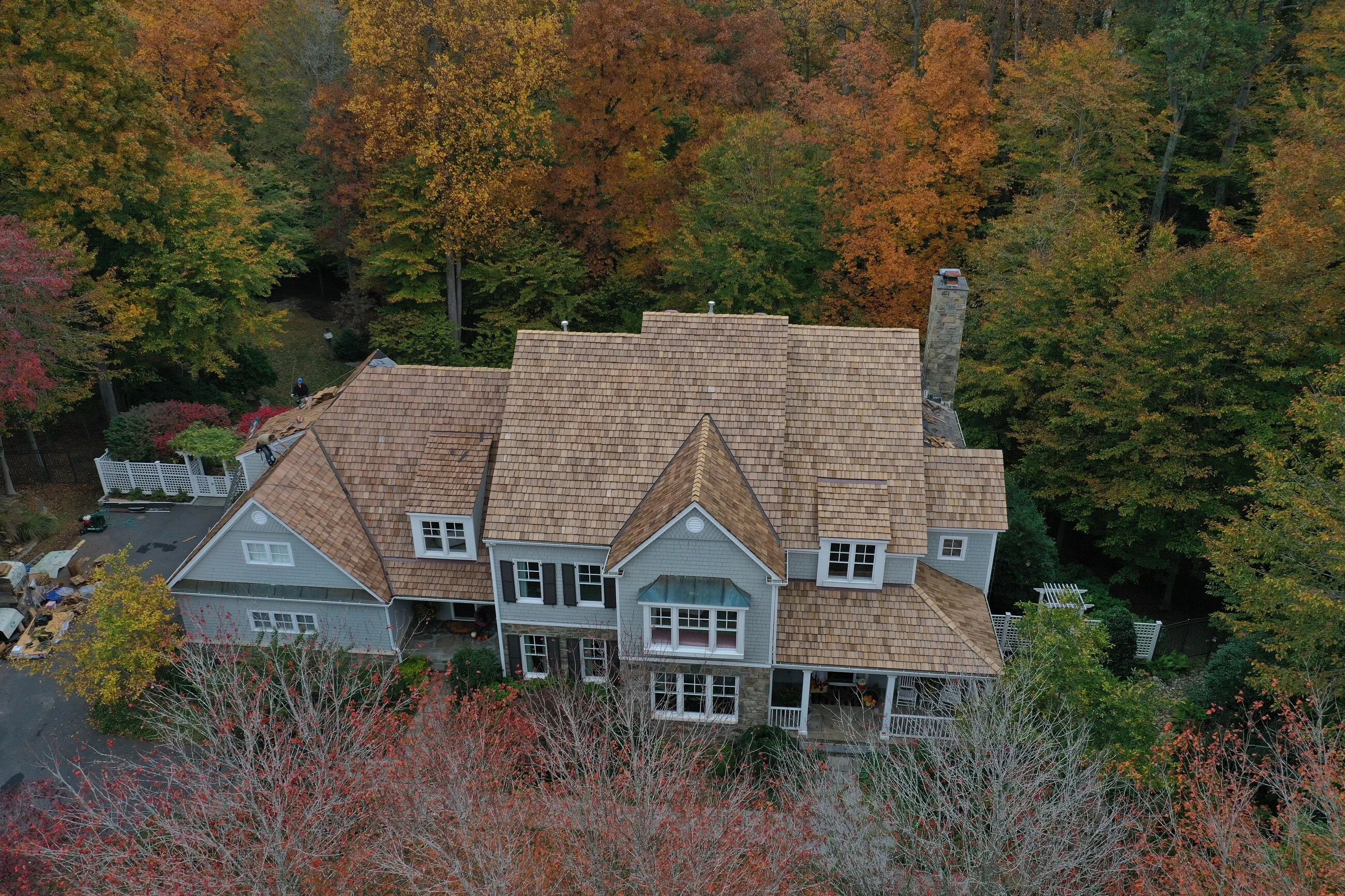 Aerial view of a shake-style roof surrounded by autumn foliage