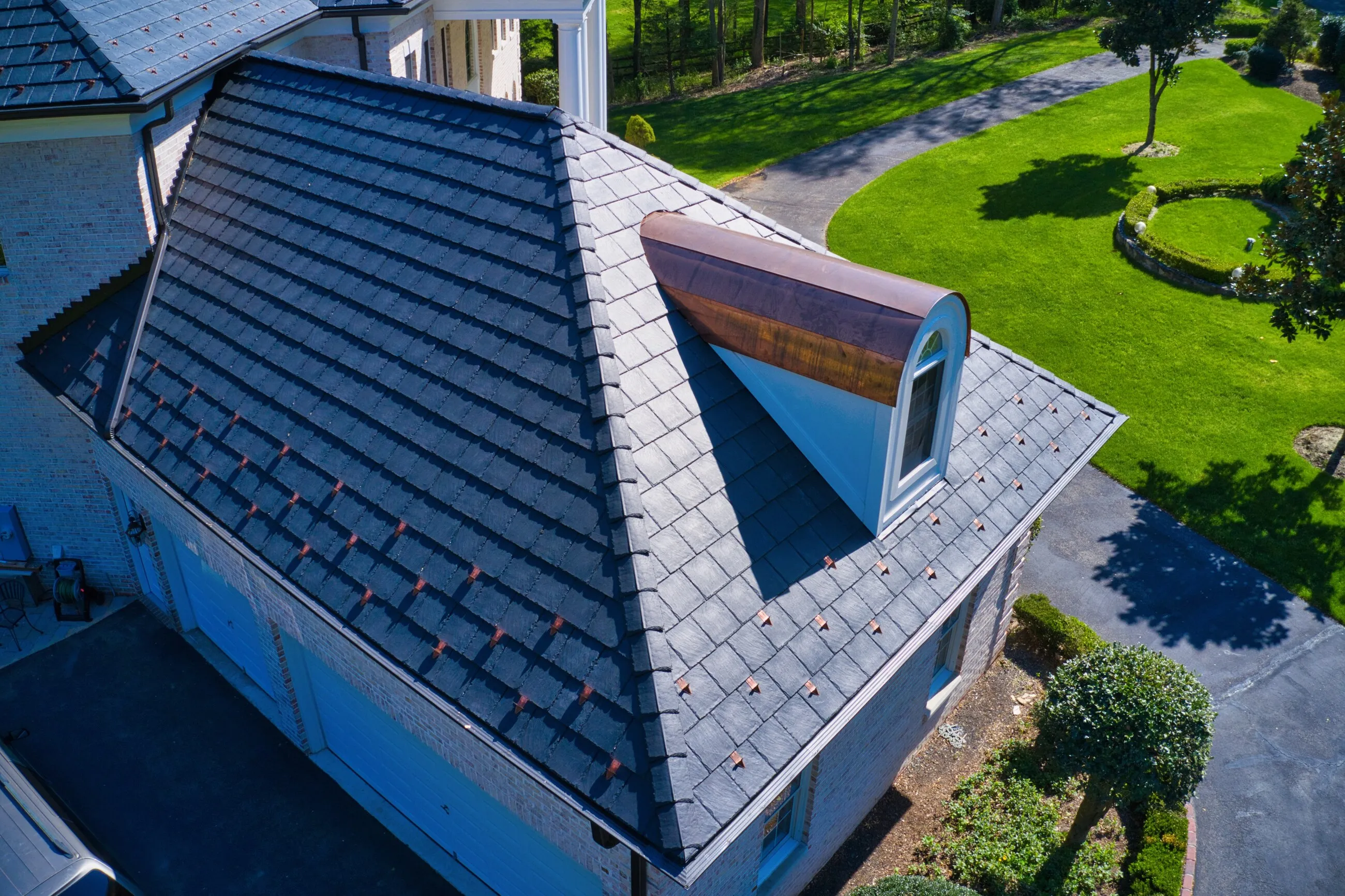 Close-up of a copper barrel dormer on a slate-style roof with copper snow guards