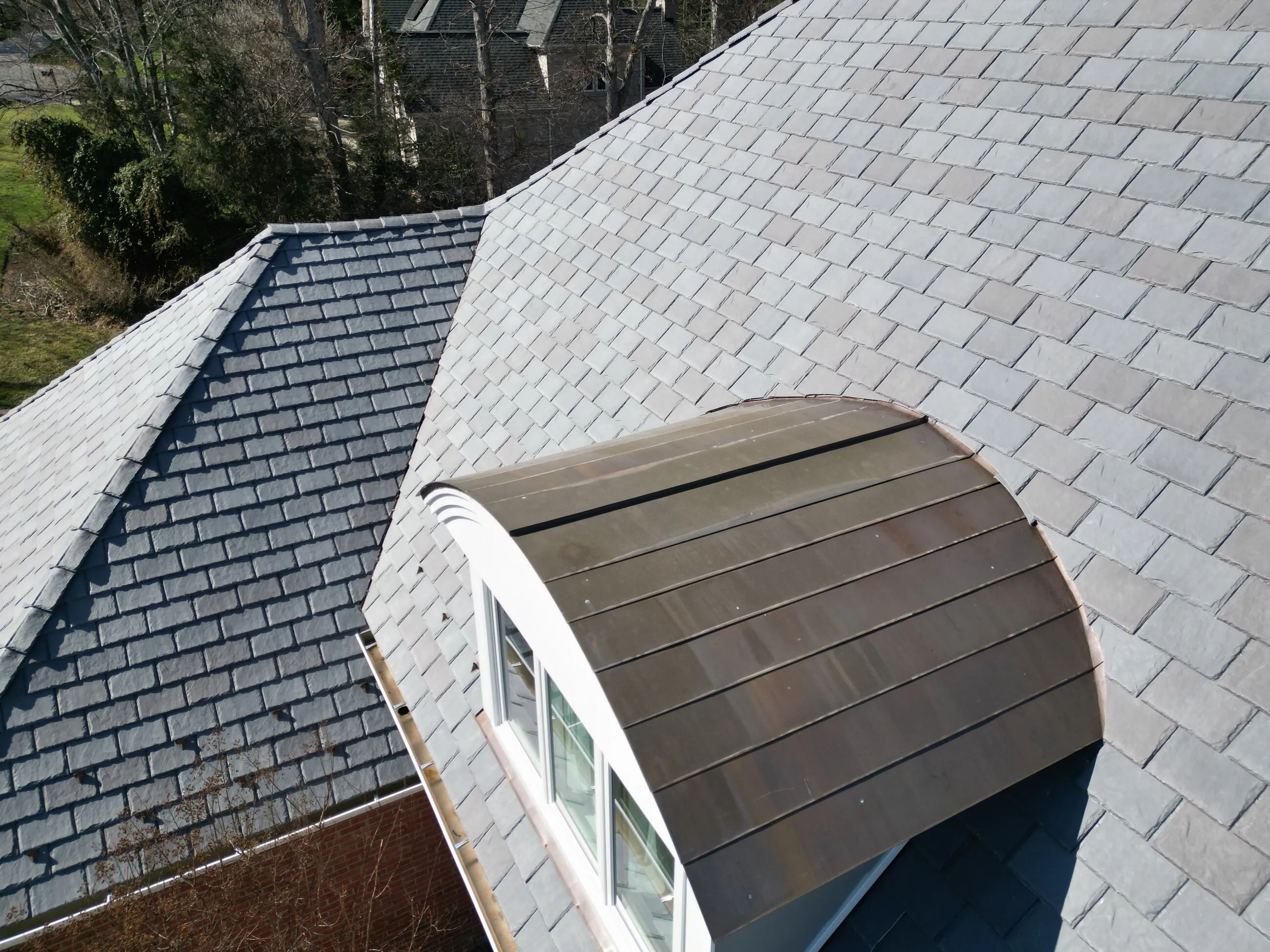 Curved copper-topped dormer set into a slate-style roof