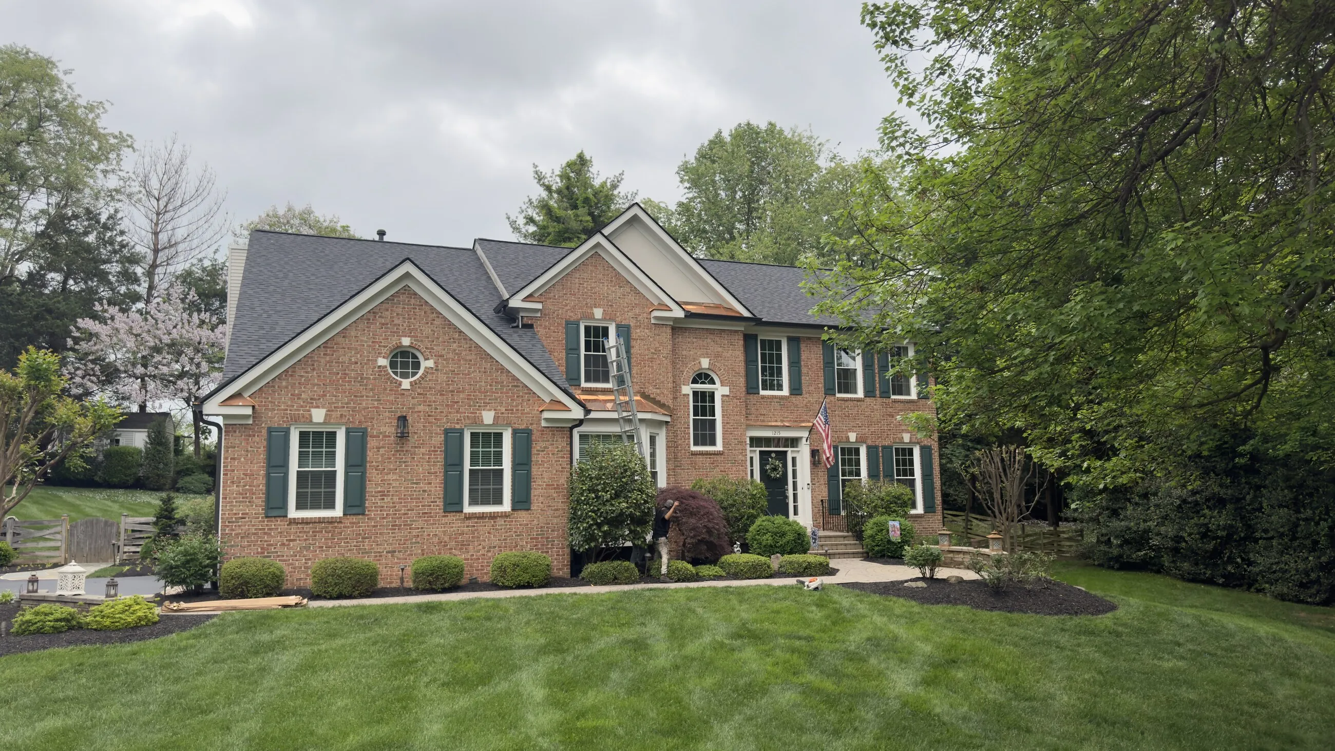 Brick colonial home with an American flag and a new architectural shingle roof