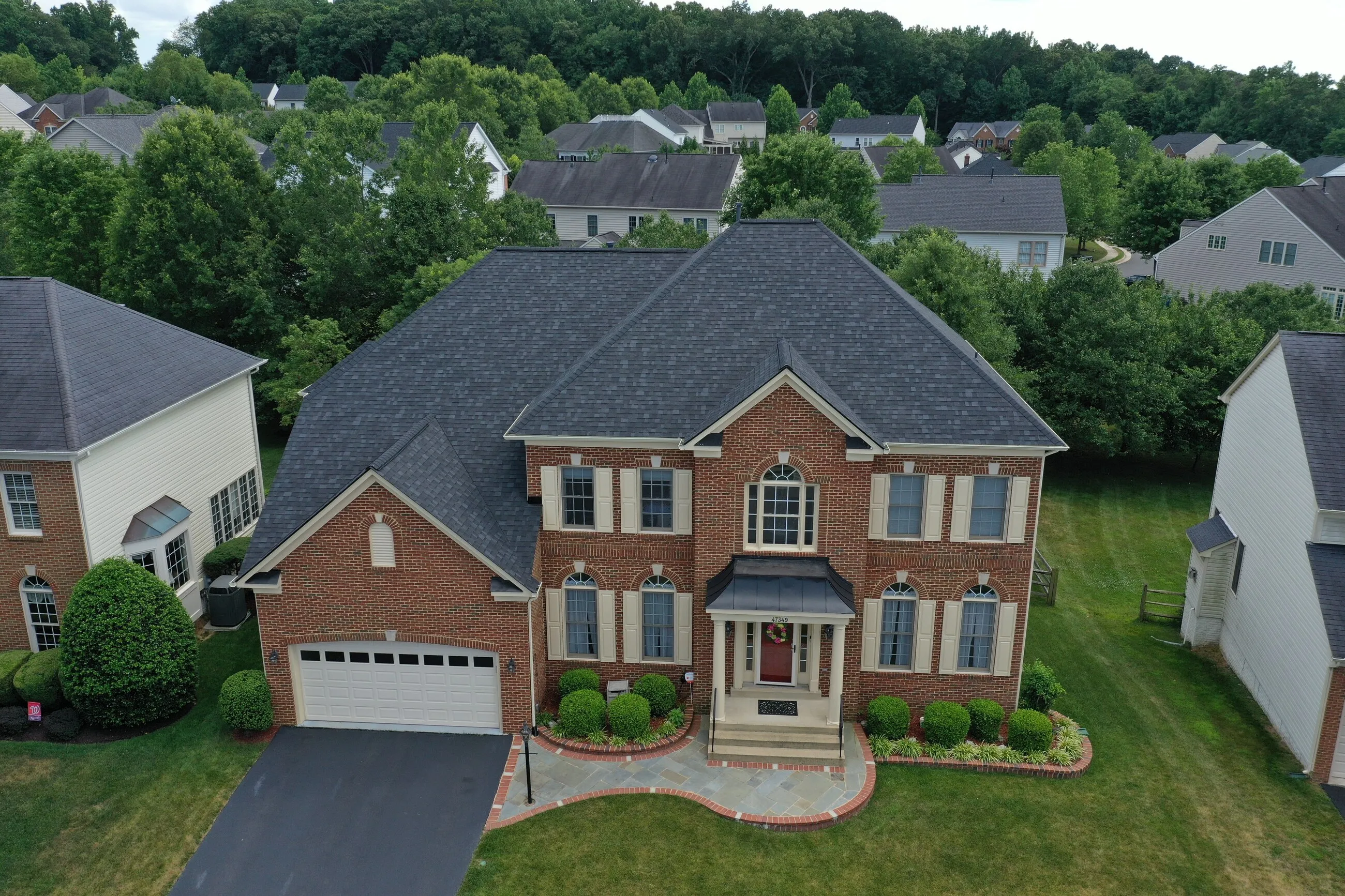 Aerial view of a brick colonial home with a new designer shingle roof