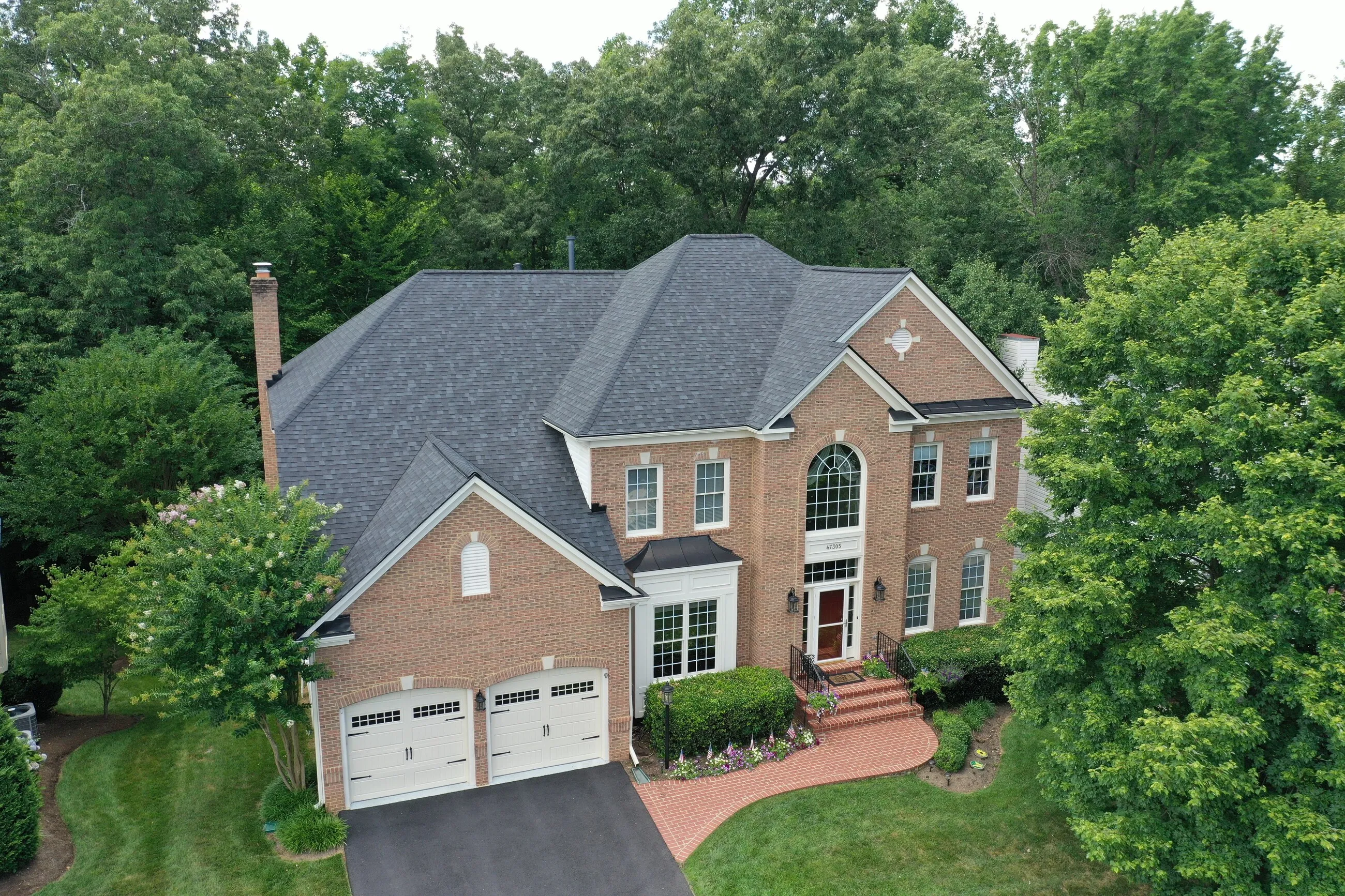 Aerial view of a brick colonial with a Palladian window and a new designer shingle roof
