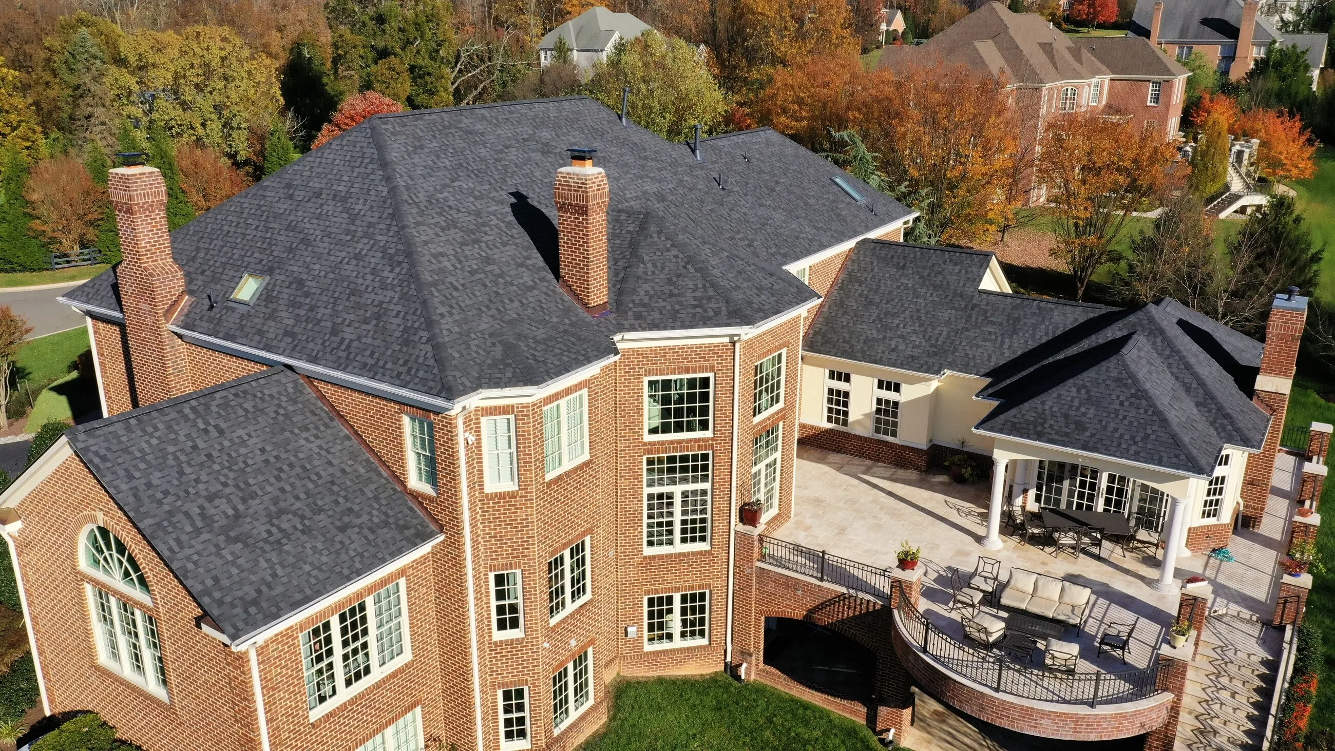Aerial view of a large brick estate with a new roof over the main house and patio wings