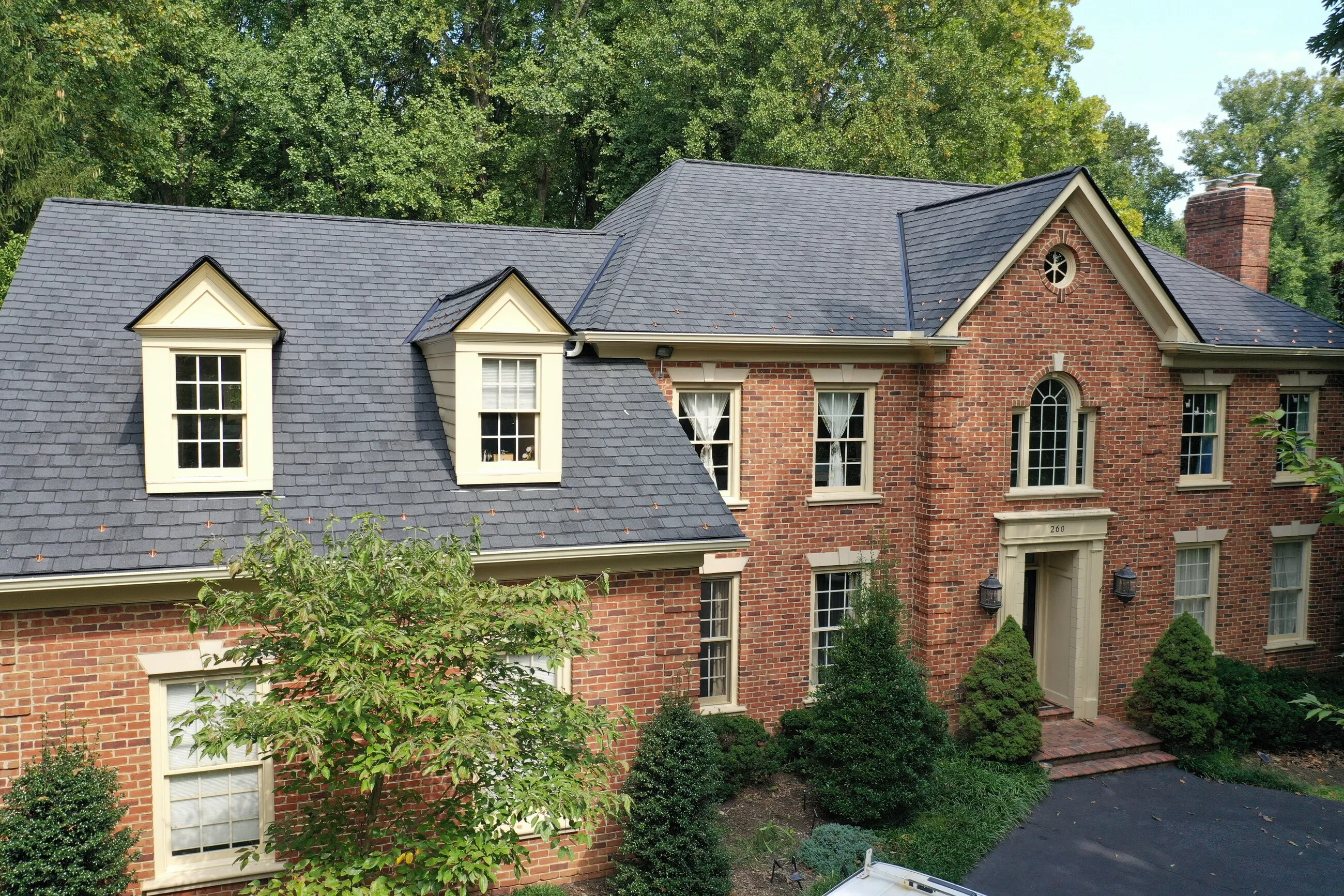 Brick Georgian home with cream dormers and a new slate-style shingle roof