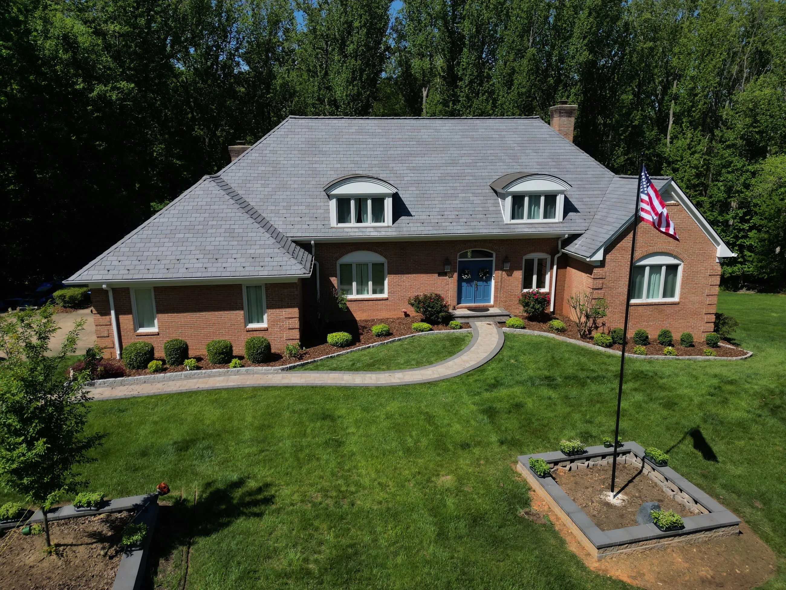 Brick home with a new slate-style roof and an American flag in the front yard