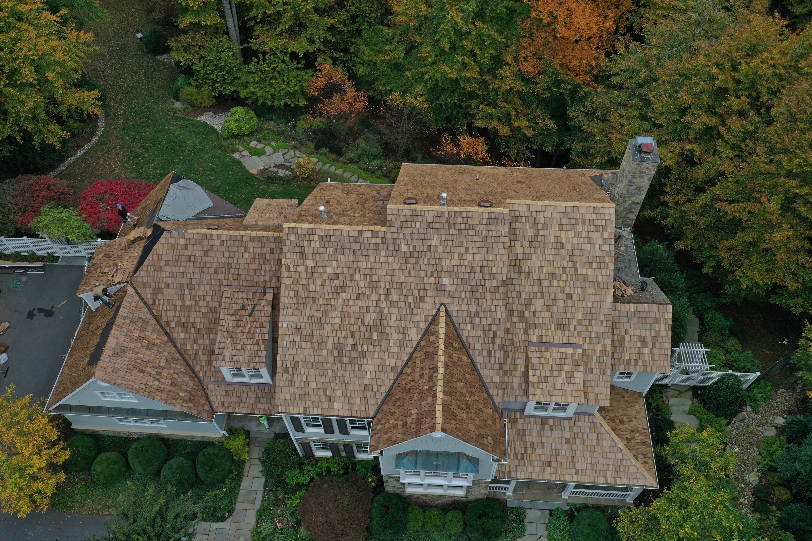 Aerial view of a completed cedar shake roof surrounded by fall foliage