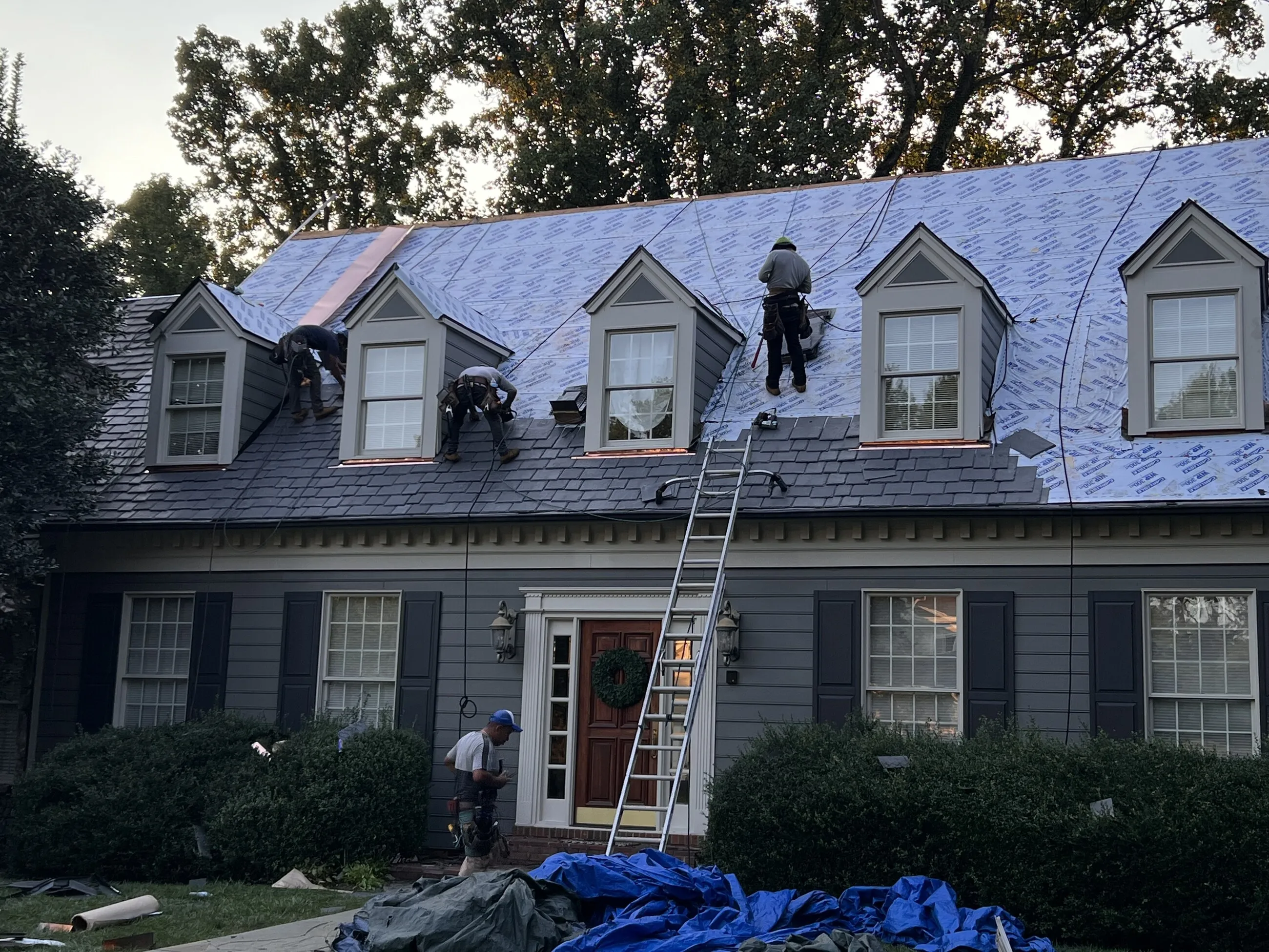 1ROOF crew working across the dormers of a home mid-replacement
