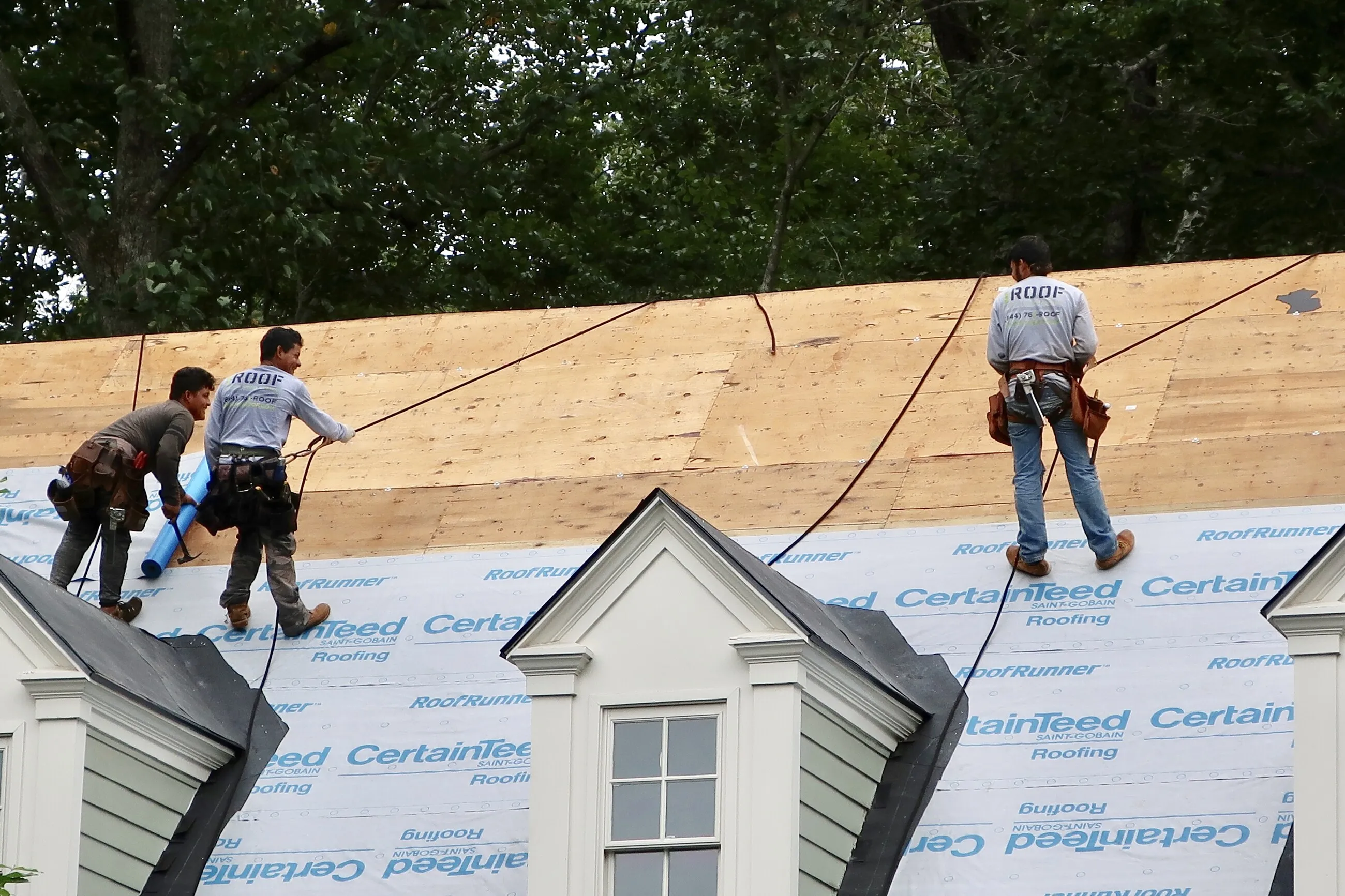 1ROOF crew installing underlayment on an open roof deck