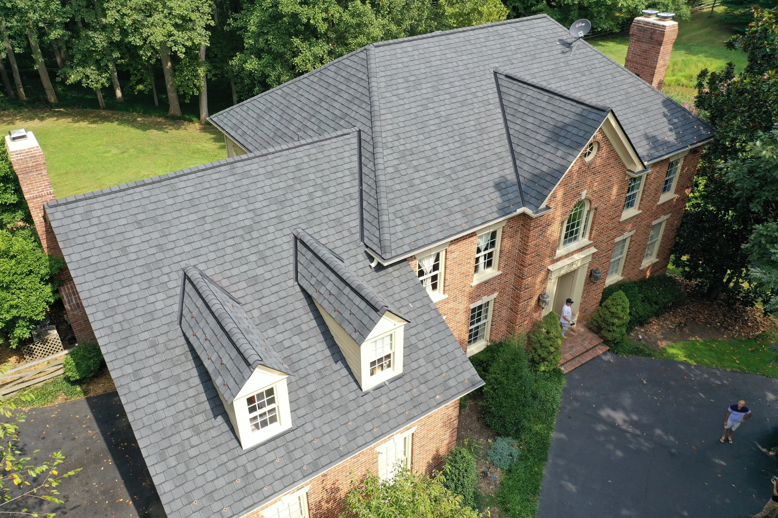 Aerial view of a brick colonial with a new designer shingle roof and dormers