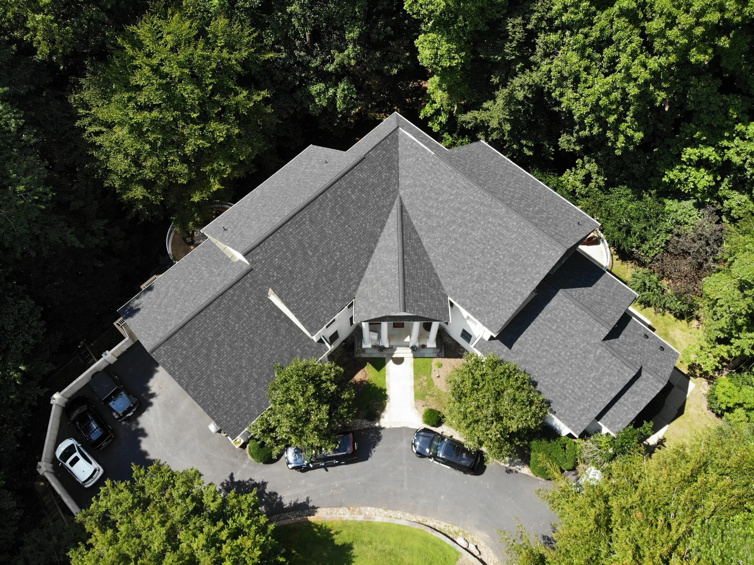 Top-down aerial view of a large estate with a new architectural shingle roof and circular drive