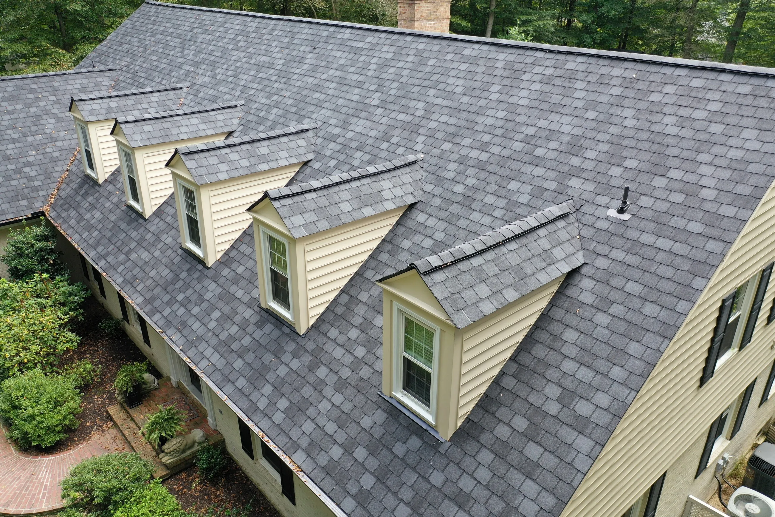 Slate-style shingle roof with five dormers on a yellow Northern Virginia home