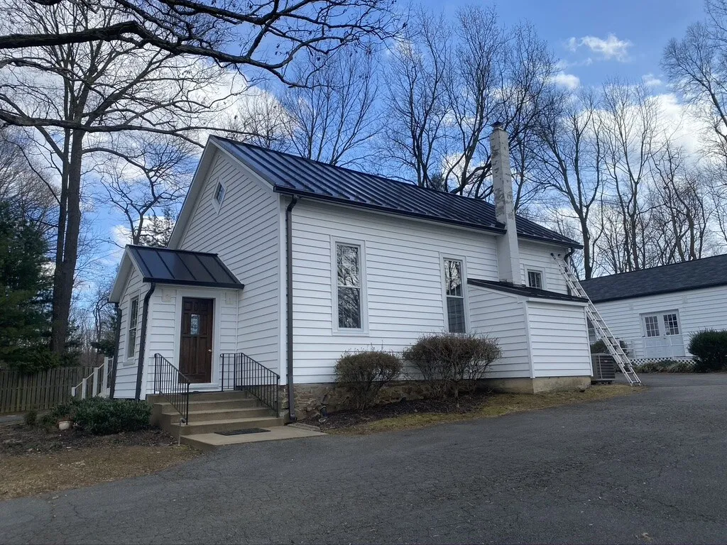 Historic white chapel with a new black standing-seam metal roof