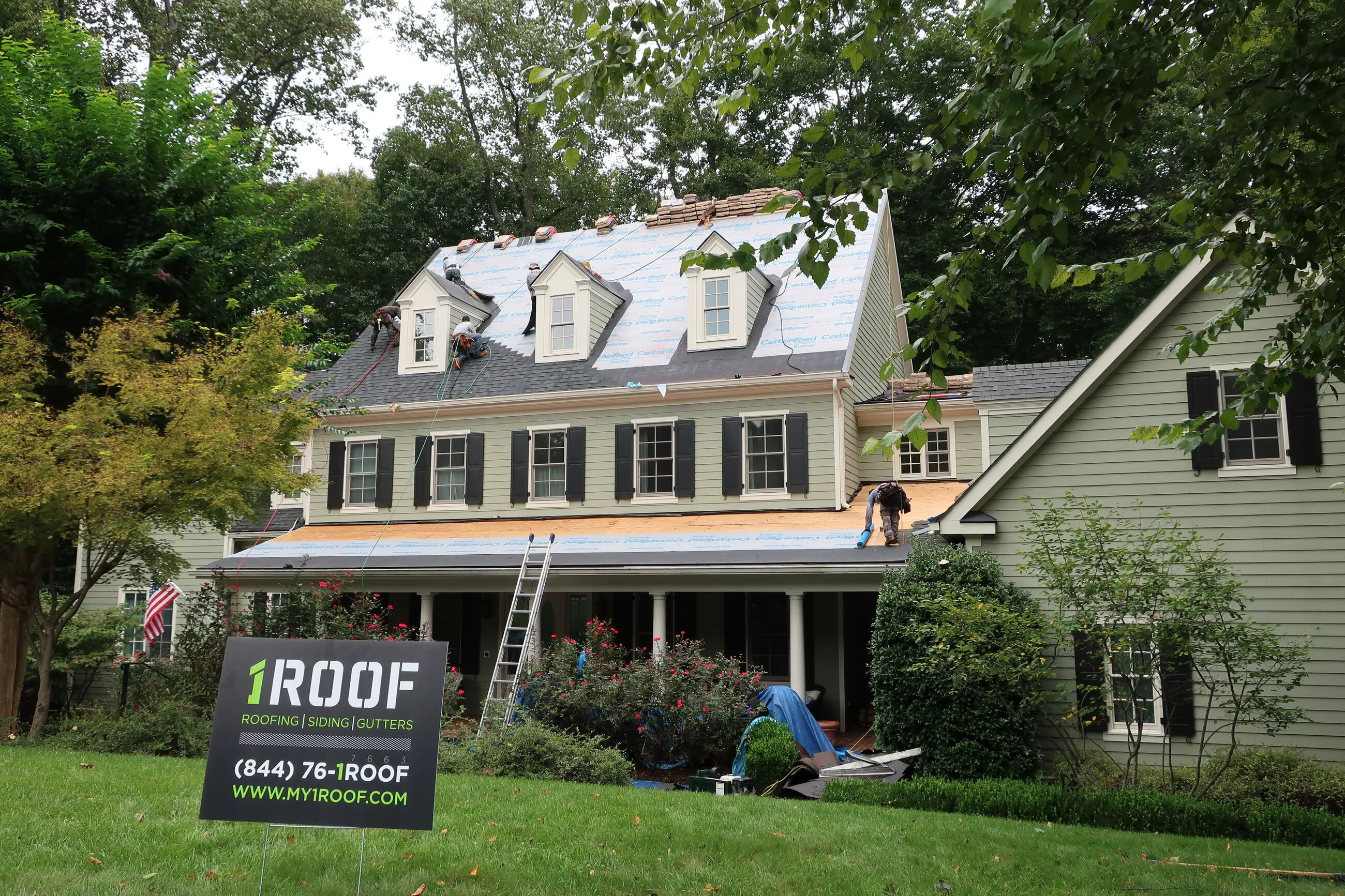 1ROOF yard sign in front of a home with a roof replacement in progress