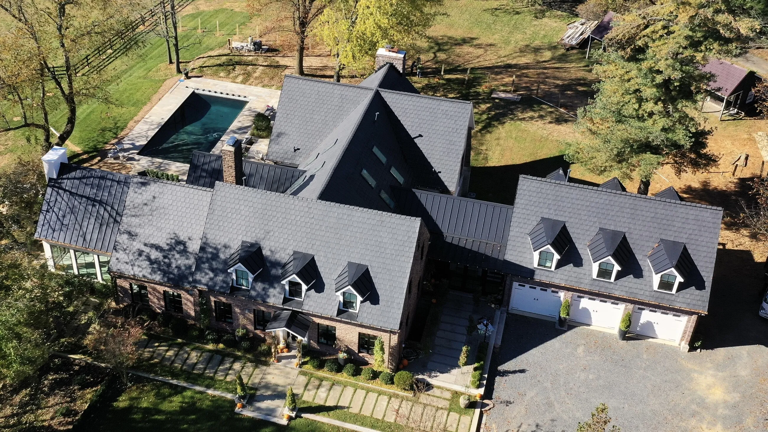 Aerial view of an estate with a new designer shingle roof, dormers and a backyard pool
