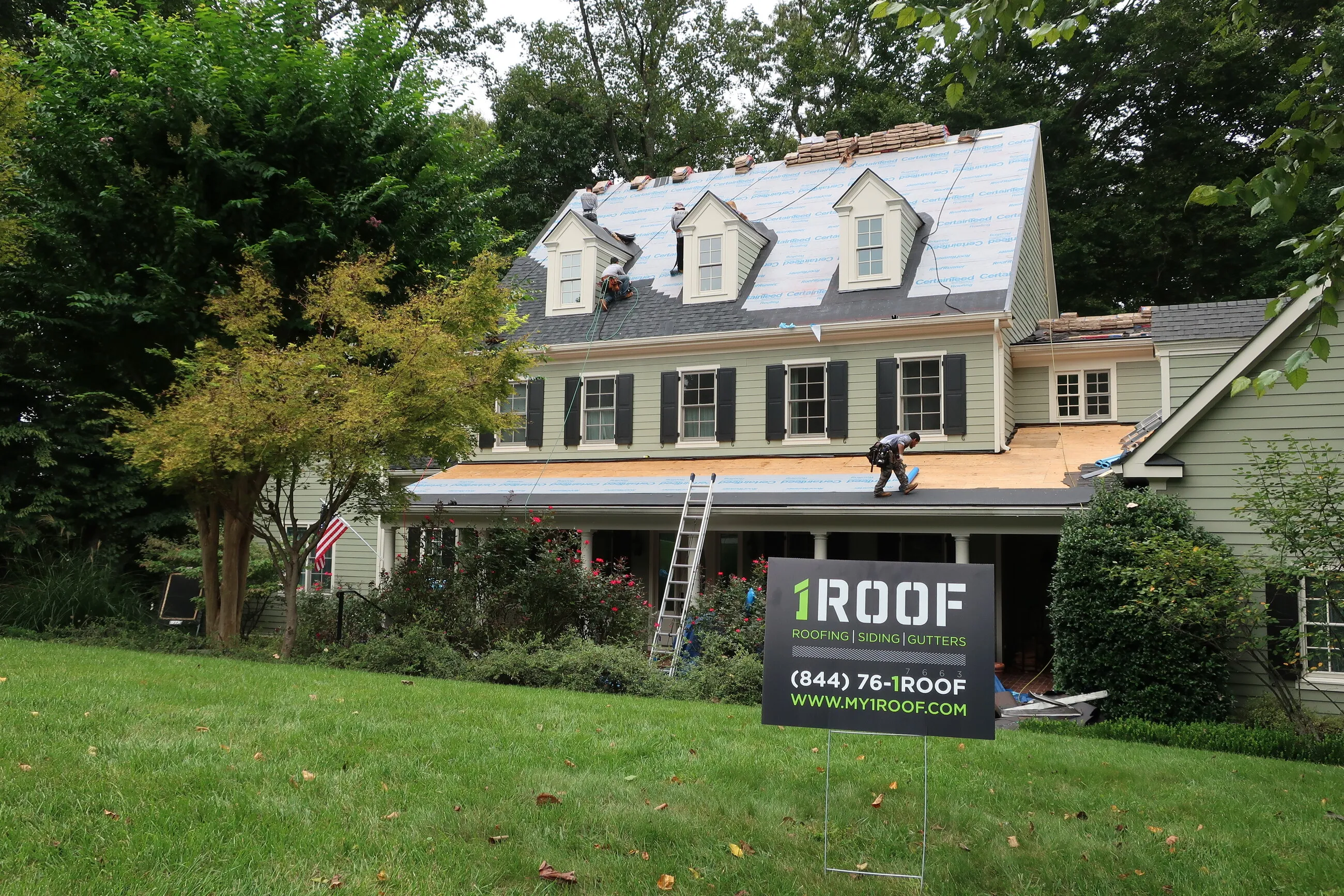 1ROOF yard sign in front of a home being re-decked during a roof replacement
