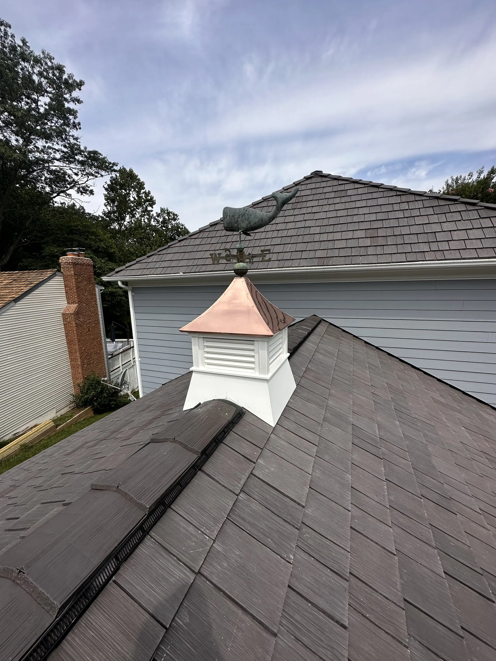 White cupola with a new copper cap on a shake-style roof ridge