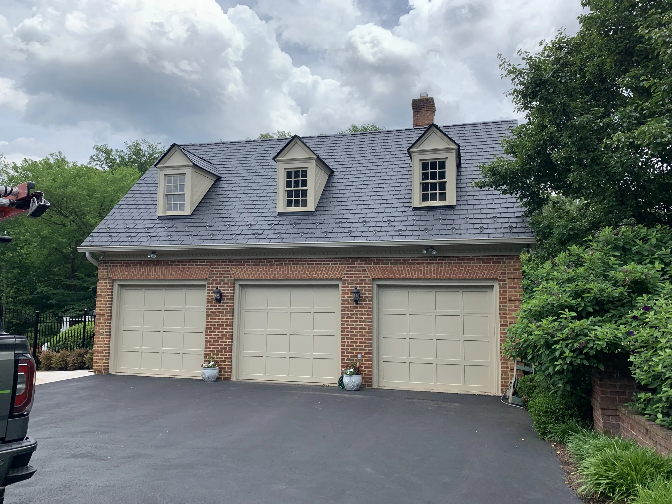 Three-car brick garage with a new slate-style roof and dormers
