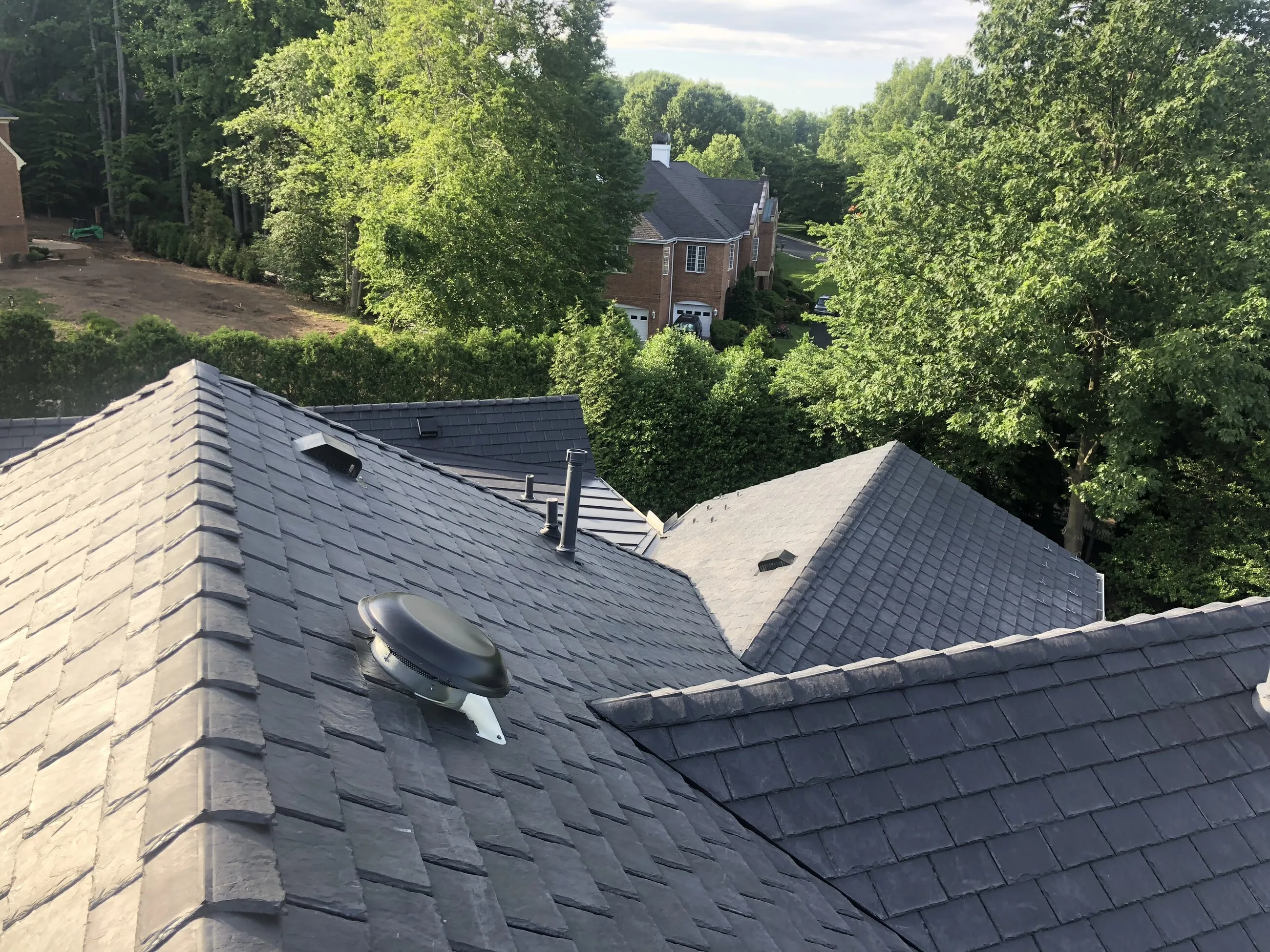 Slate-style roof planes meeting at a ridge with a dome attic vent