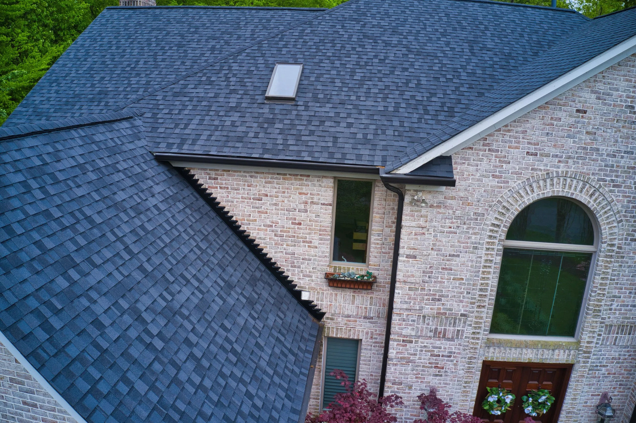 Dark slate-style roof meeting a whitewashed brick gable with an arched window