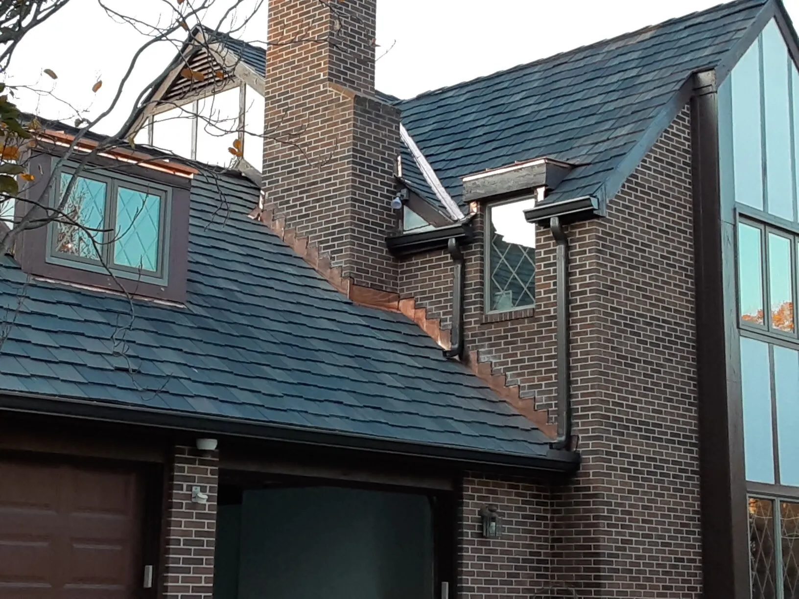 Brick Tudor home with a new slate-style roof and copper gutters and downspouts