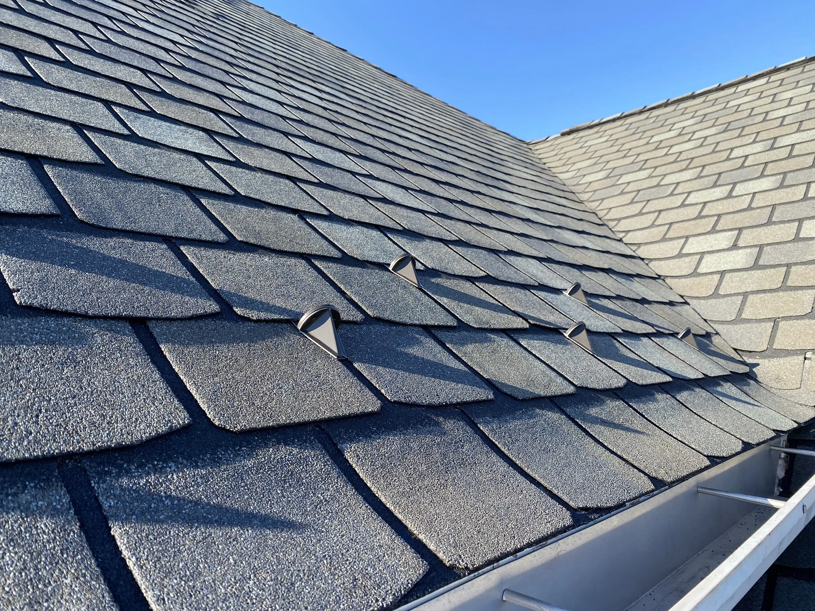 Close-up of two-tone slate-style shingles meeting at a gutter line