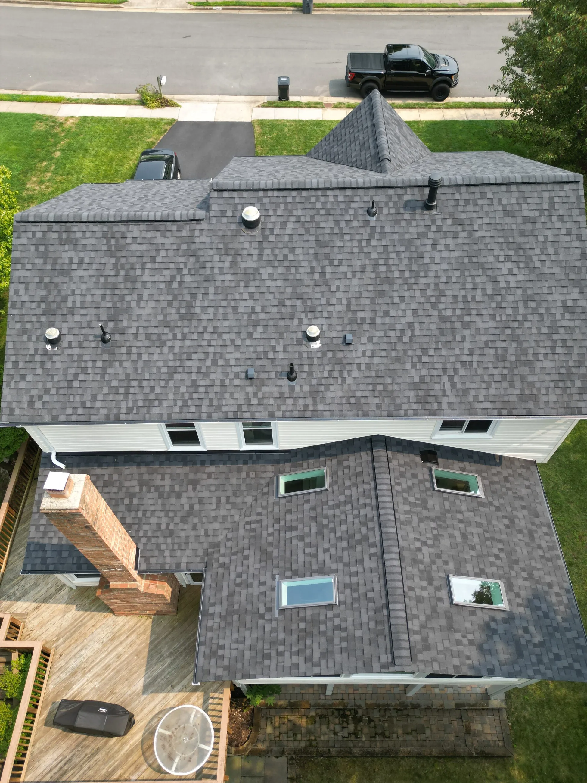 Top-down aerial of a white colonial with a new architectural shingle roof and skylights