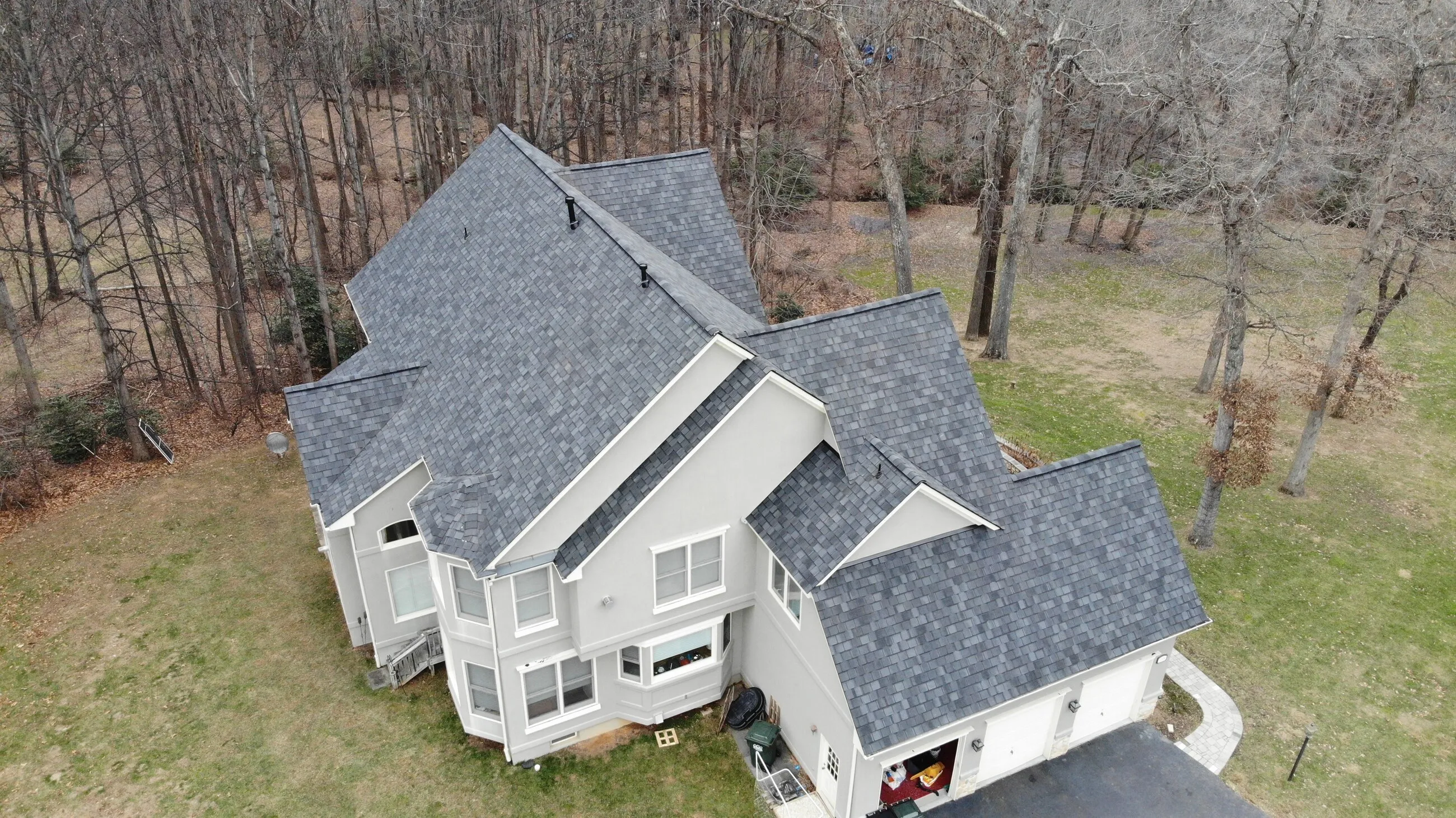 Aerial view of a colonial home with a new architectural shingle roof in winter