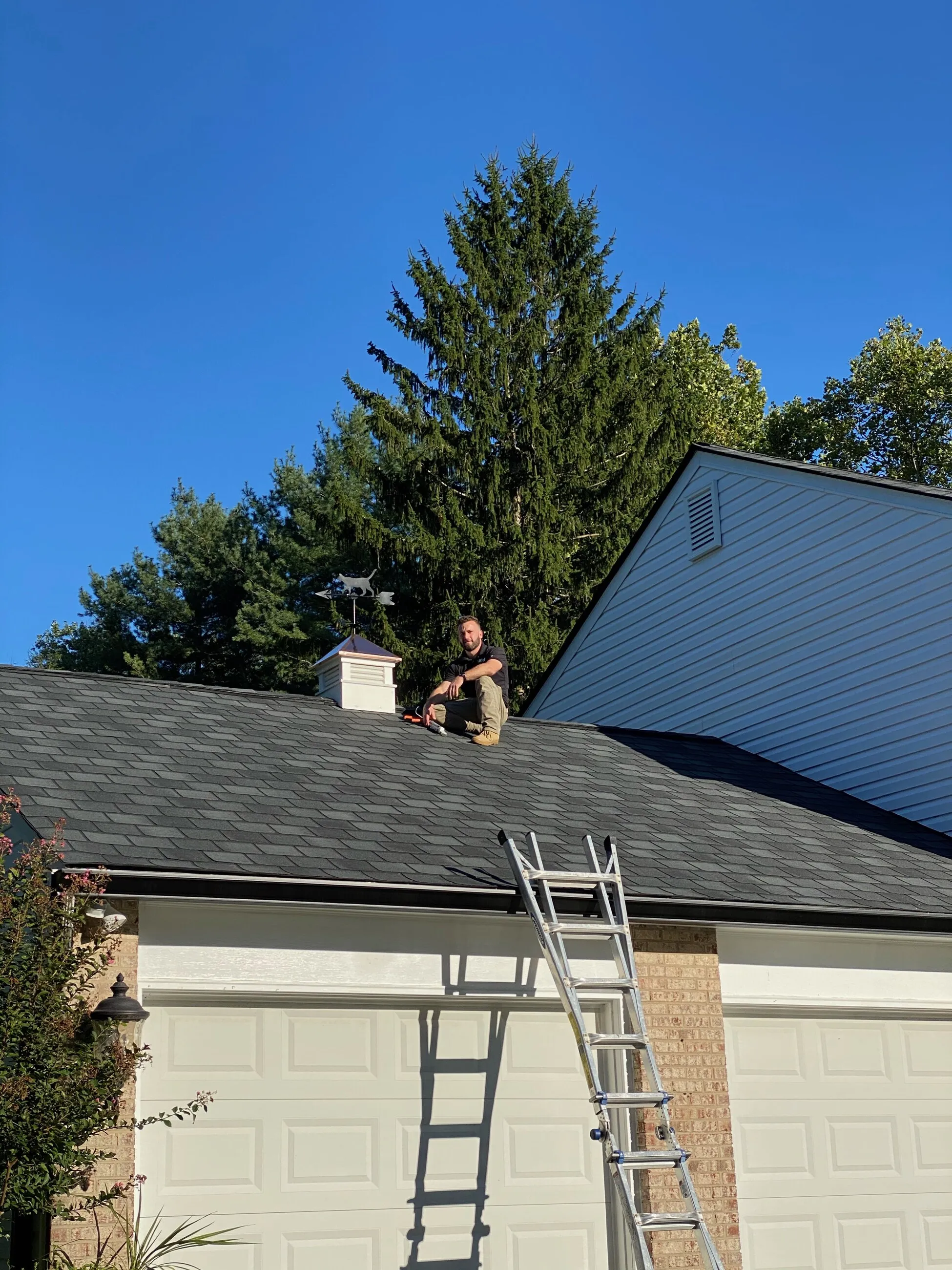 1ROOF roofer working at the ridge beside a cupola and weathervane